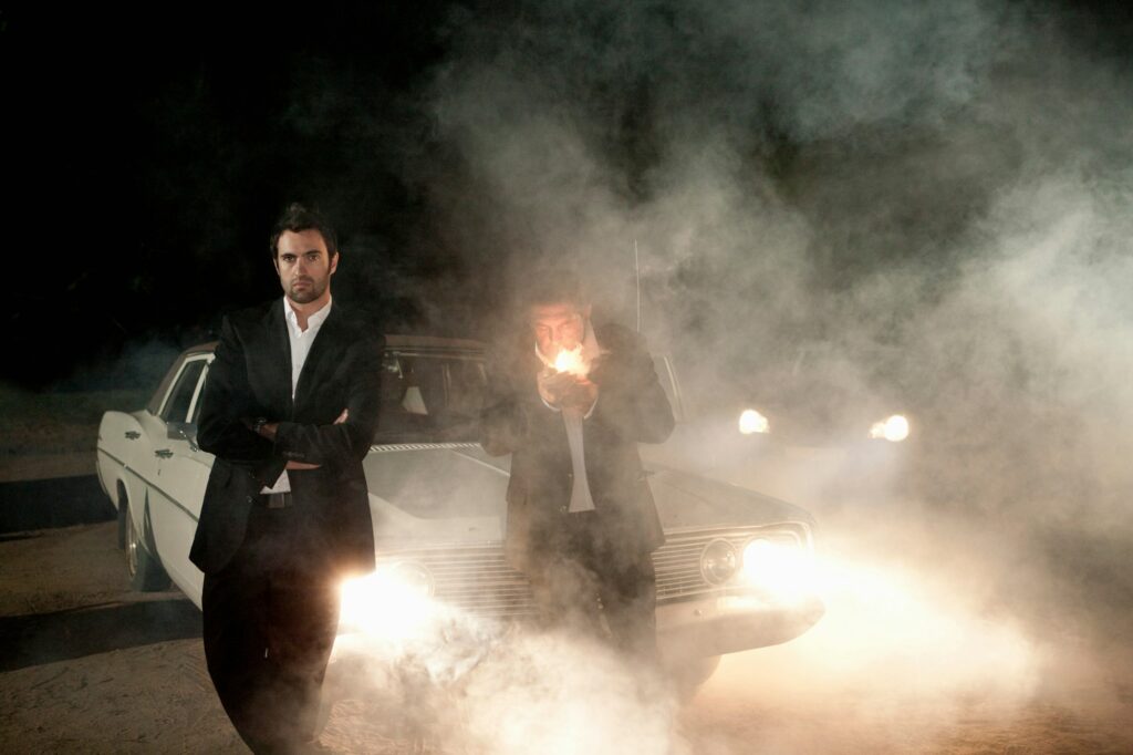 Men in suits waiting by car in fog